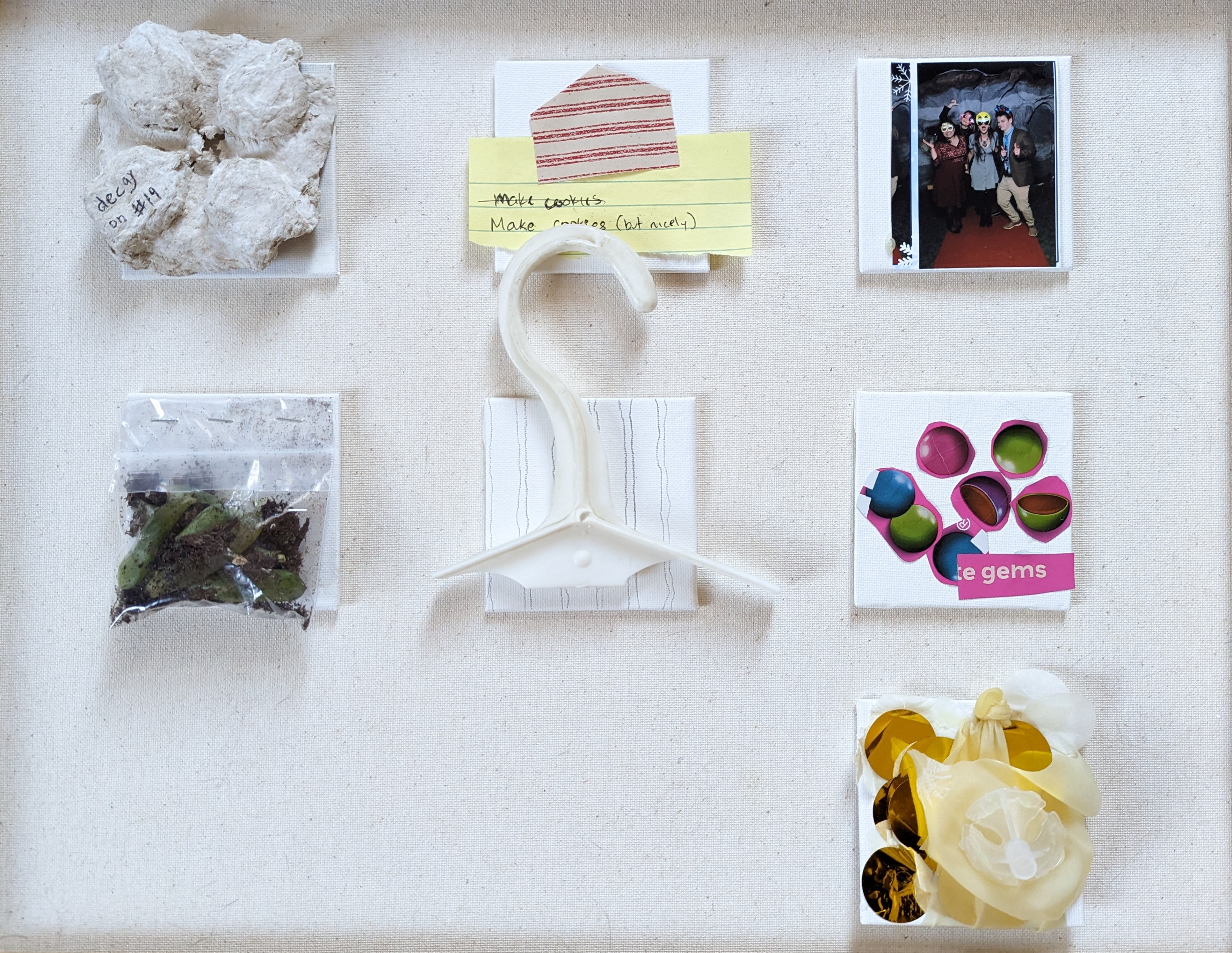 Grid of 6 assemblages on linen: white plaster rock fragments labeled 'decay on #19', yellow note reading 'make cookies / Make cookies (but nicely)' with red striped envelope flap, photobooth photo of four people, clear bag with soil and green seedlings, white plastic hanger over line drawing, open plastic gem-egg magazine cutout, and crinkled candy wrappers in a bag.