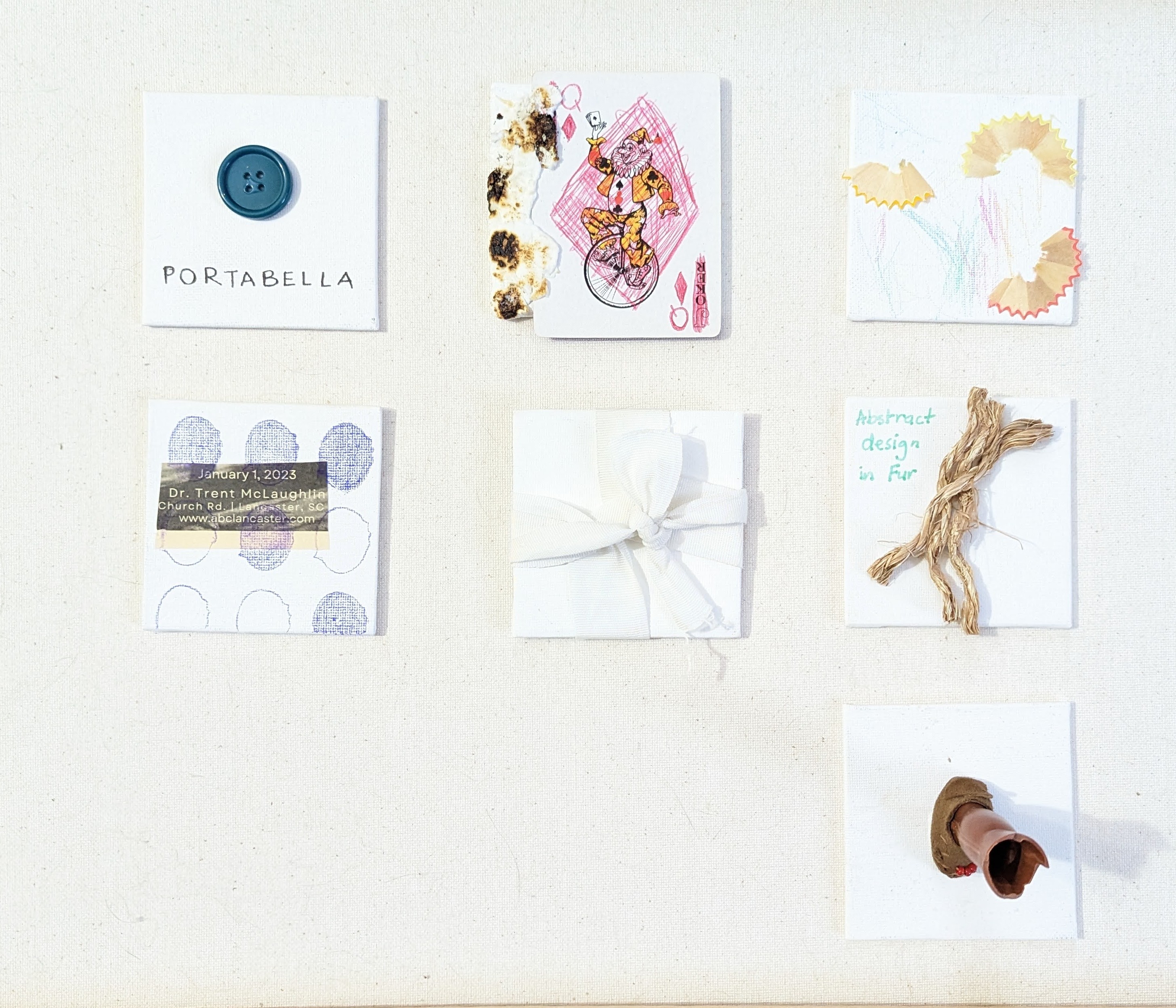 Grid of 7 assemblages on linen: black binder clip on canvas, crinkled gold foil with packaged object, 'MONKEY' label with fishing hook sketch, drawn orange glasses with attached black plastic frame, shibori-dyed fabric strips in indigo and yellow-olive, lavender resin dot cabochons, and a tied red grosgrain ribbon bow.