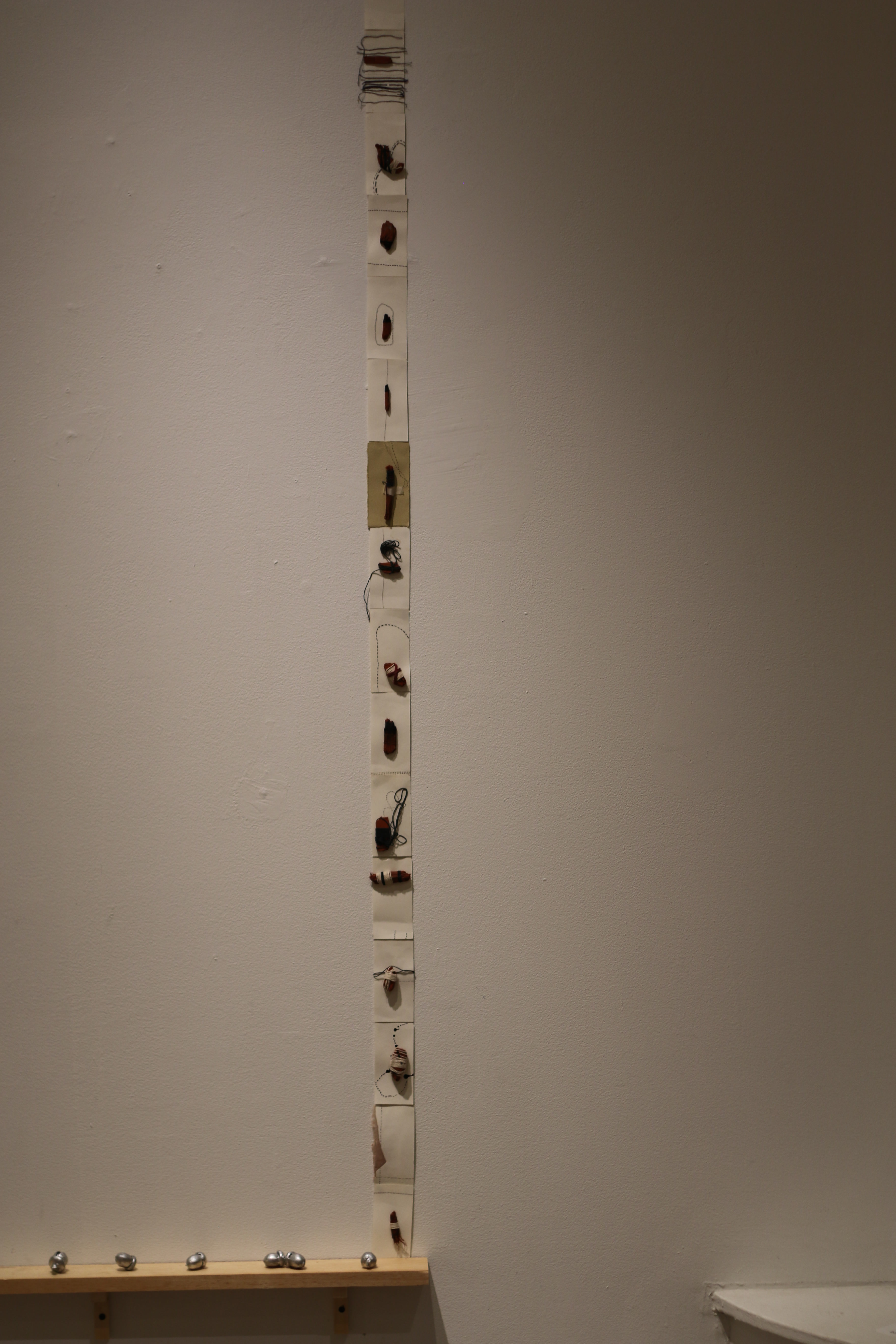 Installation view of re:trace showing the Calendar artwork mounted against a white gallery wall alongside suspended sculptures and thread works.