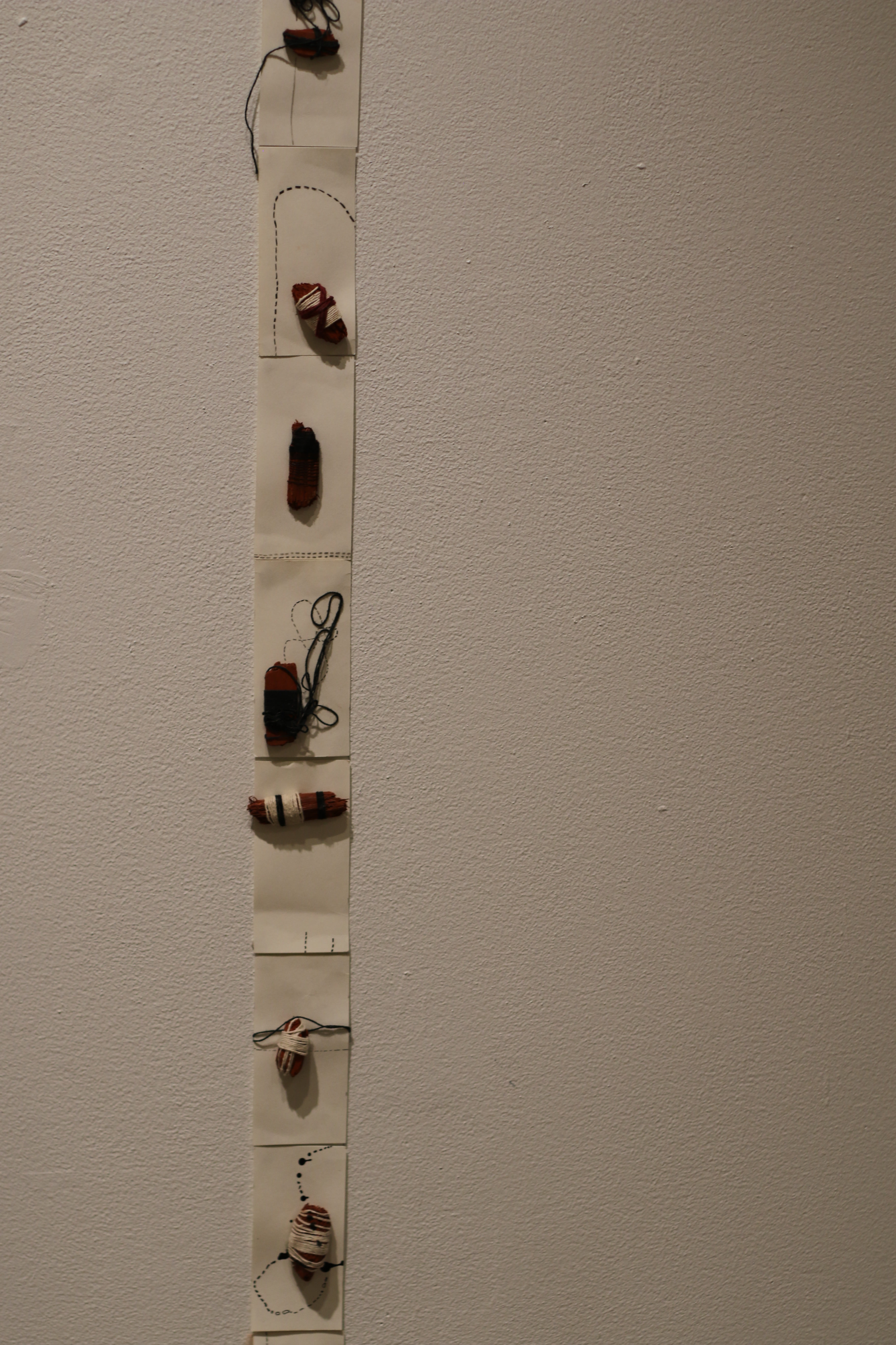 Detail view showing the Calendar installation in re:trace, highlighting small mulch-and-thread grid units pinned in a horizontal sequence on the wall.